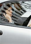 Businessman sitting in car, using cell phone, viewed through window