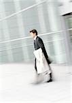 Businessman walking, holding overcoat, blurred