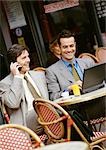 Zwei Geschäftsleute sitzen an Café-Terrasse, mit Handy und Laptop-computer