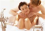 Woman taking bath, man massaging her shoulders