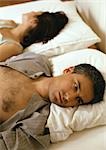 Mann und Frau im Bett, Köpfe auf Kissen, mit Blick auf entgegengesetzte Richtungen, Kopf und Schultern liegend