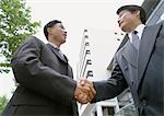 Two businessmen shaking hands, low angle view