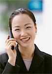 Businesswoman using cell phone, smiling at camera, portrait