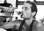 Man drinking from bottle, close-up, b&w