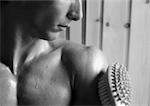Bare-chested man, brush on arm, close-up, b&w