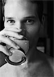 Man drinking and looking at camera, close-up, b&w