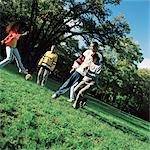 Young people kicking soccer ball on grass