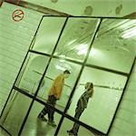 Young people talking together in subway station corridor, viewed in mirror.