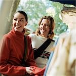 Young women smiling next to rack of clothing, outdoors