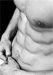 Barechested man's flexed abdomen, close-up, black and white.