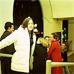 Young woman in coat smiling at camera, group of young people in background