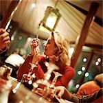 Young woman holding cigarette and looking over shoulder at table in restaurant