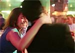 Young man and woman talking in bar, woman with hand around man's neck