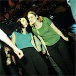 Two young women talking on dancefloor in nightclub