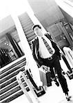 Businessman getting off escalator, running and holding briefcase, blurred, b&w.