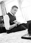 Businessman working, sitting on edge of bed in hotel room, blurred, b&w.