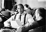 Businessmen sitting together looking over papers, b&w.