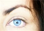 Woman's blue eye, eyebrow raised, blurred close up.