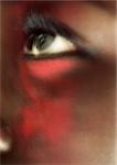 Woman's eye looking up with red make-up on face, close-up, blurred