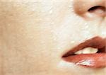 Woman wearing red lipstick, close up of open mouth and wet skin, cropped, blurred.