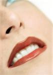 Femme portant le rouge à lèvres, gros plan, vue partielle du visage, floue.