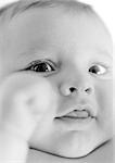 Baby's face, sticking tongue out, fist blurred in foreground, B&W.