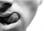 Man's lower face, licking lips, close-up, blurred, black and white.