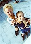 Mature woman and young girl on in-line skates, making faces at camera, high angle view