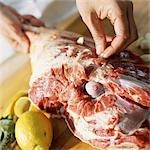 Close-up of hands preparing leg of lamb