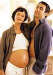 Pregnant woman standing with man, looking at camera, portrait