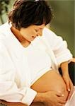 Pregnant woman with hands on stomach, looking down