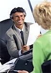 Businessman at desk, smiling at woman