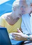 Femme mûre et un homme assis à l'extérieur avec ordinateur portable