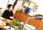 Man sitting at desk in office, side view