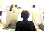 Woman working at computer in office, blurred, rear view