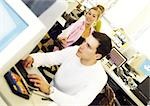 Woman smiling, man working on computer in office