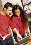 Man holding book and woman looking at laptop computer