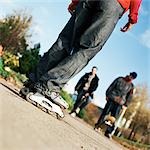 Young people, on wearing in-line skates, others with skateboards, low section