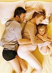 Mann, eine schwangere Frau und Kind liegen im Bett, erhöhte Ansicht