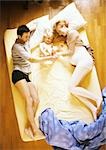 Man, pregnant woman and child lying on bed, elevated view