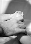 Father's hand holding baby's feet, close-up, b&w