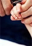 Adult cutting baby's fingernails, close-up