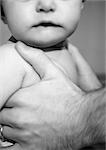 Baby held in father's hands, partial view, close-up, b&w