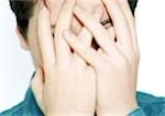 Teenage boy with hands covering face, close-up
