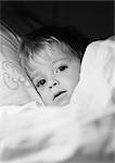 Little girl in bed under blanket, close-up, b&w