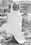 Little girl wrapped in towel on beach, b&w