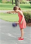 Girl playing with ball outside, side view, blurred motion