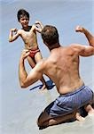 Man and child facing each other, flexing on beach
