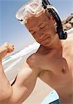 Close-up of man flexing bicep with mask and snorkel on head at the beach