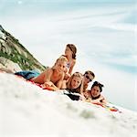Adolescents se trouvant sur des serviettes de plage au bord de la mer